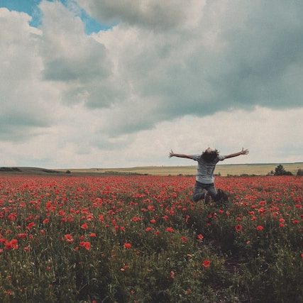 Person in a field of flowers jumping for joy Photo by Catalin Pop on Unsplash