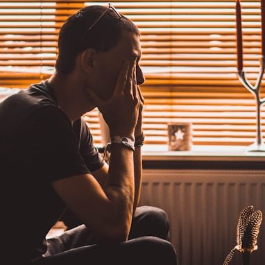 Man sitting on chair covering his eyes Photo by christopher lemercier on Unsplash